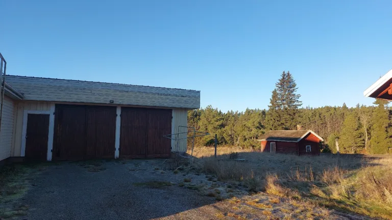 Autotalli ja taustalla vanha pihasauna